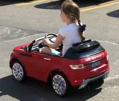 little girl enjoying her ride-on red car toy